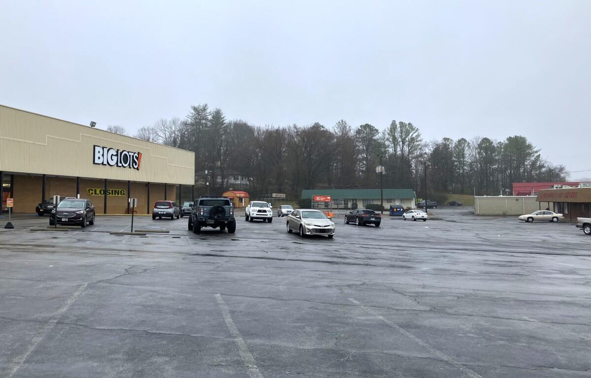 The Big Lots parking lot on Riverside Drive, with the proposed site for the apartment complex shown on the hillside at right, on Feb. 12, 2025. (Chris Smith)