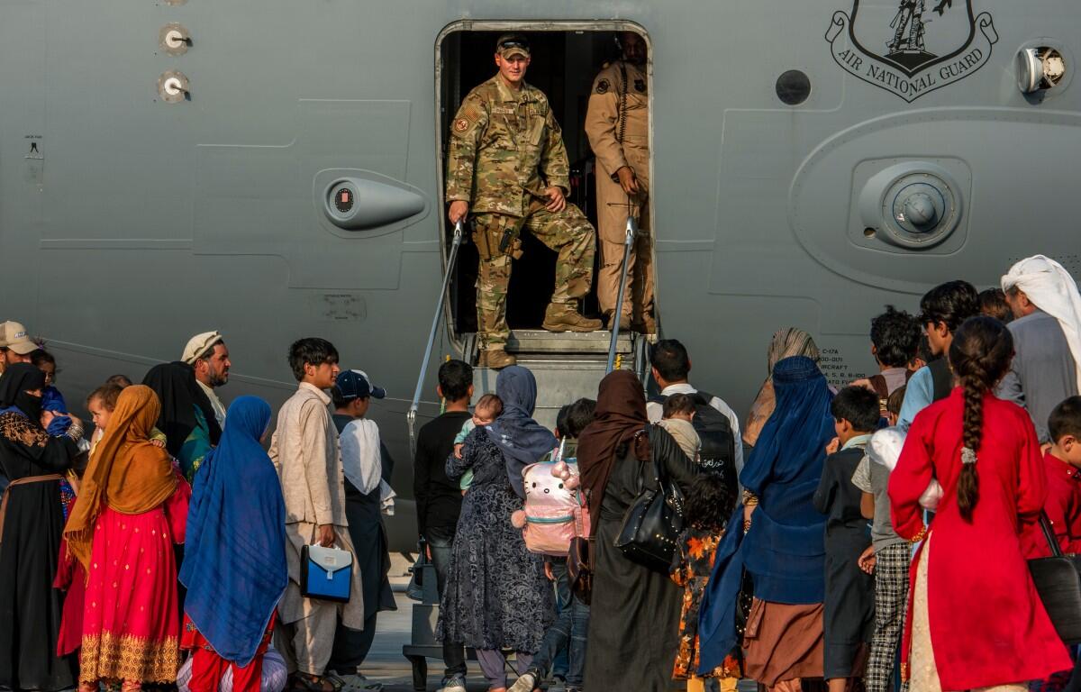 Service members stand at a doorway as Afghan evacuees prepare to board an aircraft, Aug. 22, 2021, at Al Udeid Air Base, Qatar. (Airman 1st Class Kylie Barrow/U.S. Air Force via AP, File)