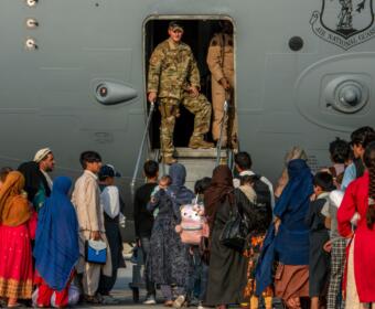 Service members stand at a doorway as Afghan evacuees prepare to board an aircraft, Aug. 22, 2021, at Al Udeid Air Base, Qatar. (Airman 1st Class Kylie Barrow/U.S. Air Force via AP, File)