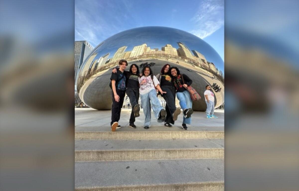 Five friends jump in unison in front of Chicago's Cloud Gate sculpture (The Bean), with the city skyline reflected on its curved surface.