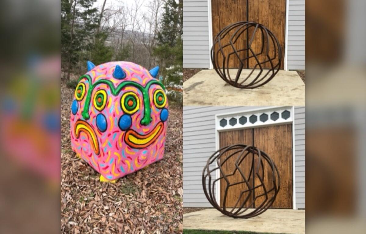 Colorful round sculpture resembling a smiling face with blue horns on a leaf-covered ground.