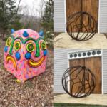 Colorful round sculpture resembling a smiling face with blue horns on a leaf-covered ground.