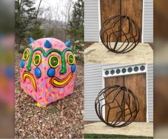 Colorful round sculpture resembling a smiling face with blue horns on a leaf-covered ground.