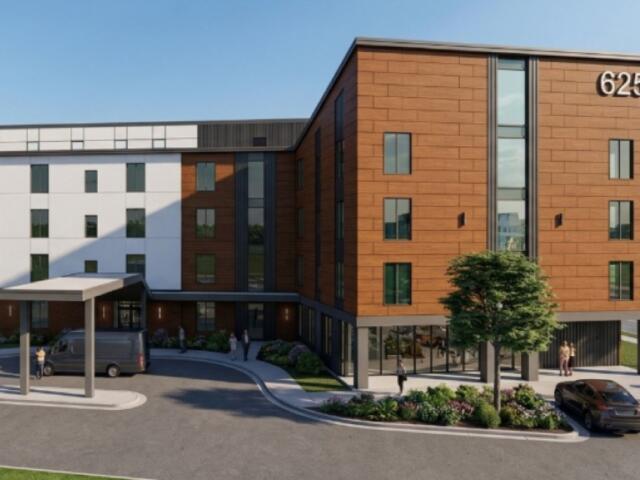 Modern four-story brick-and-white building with the number 625, glass entry, and landscaped walkway and driveway with cars parked nearby