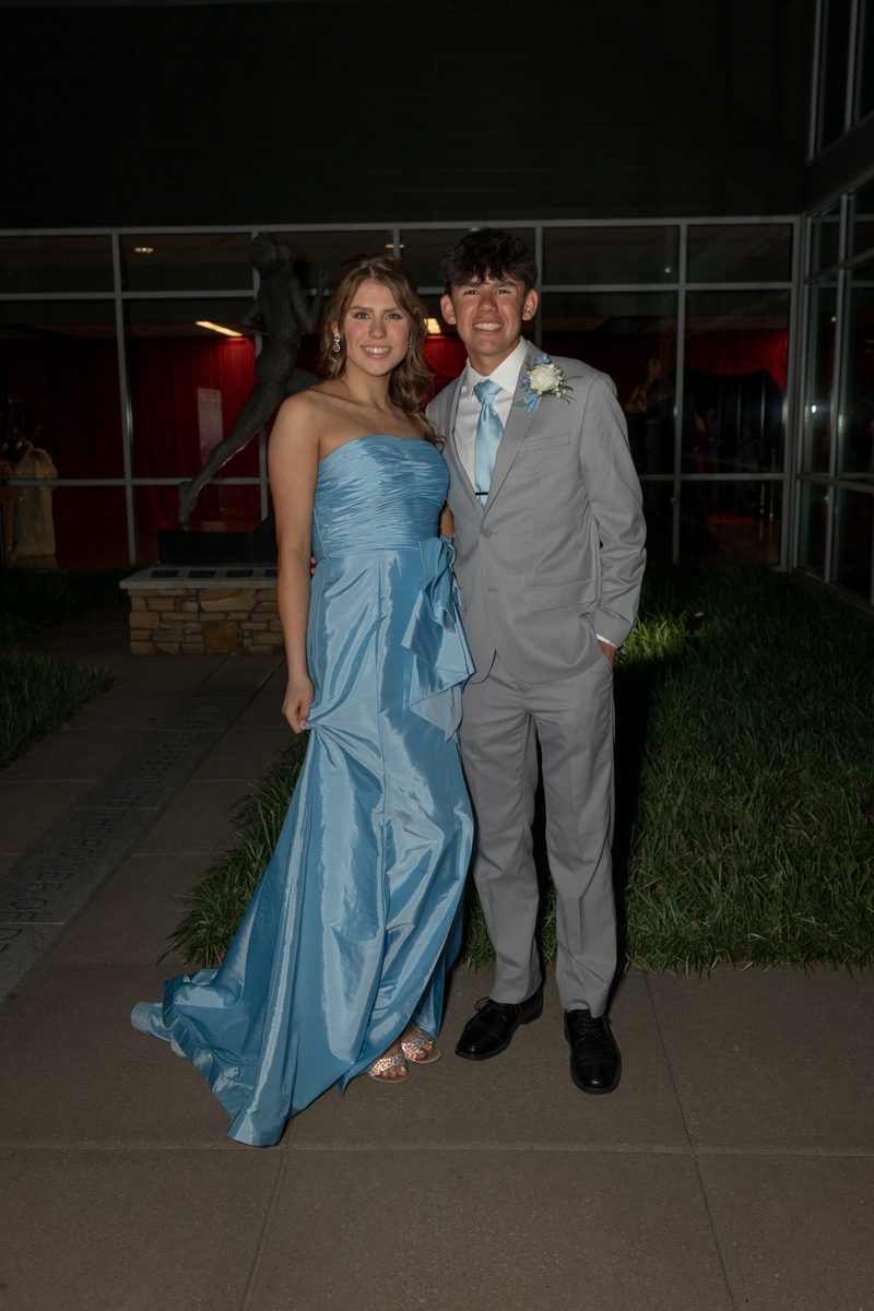 Young woman in a light blue strapless gown standing beside a young man in a gray suit with a blue tie.