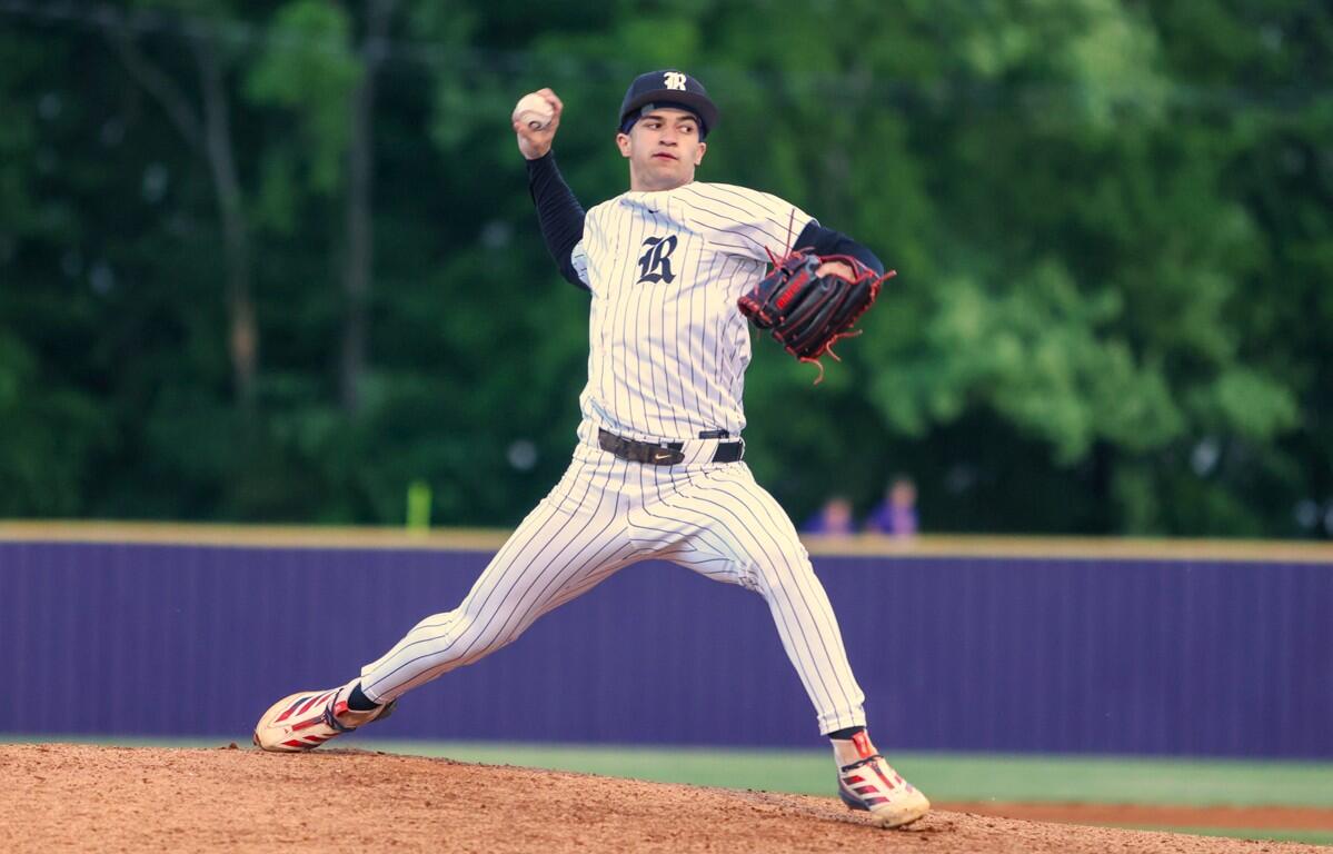 Baseball pitcher in a white pinstripe uniform winds up on the mound, throwing with his right arm, glove ready on his left hand.