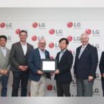 Seven men in business attire pose for a photo in front of an LG backdrop; two in the center hold a framed certificate as an award is presented.