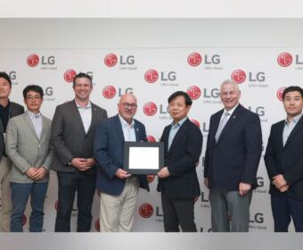 Seven men in business attire pose for a photo in front of an LG backdrop; two in the center hold a framed certificate as an award is presented.
