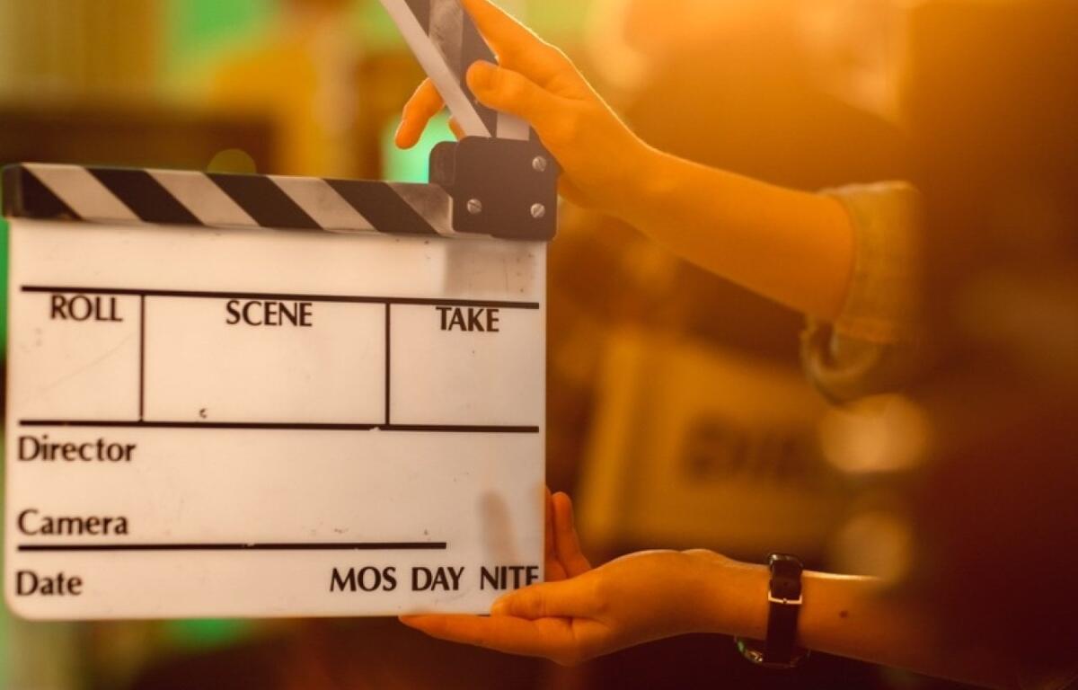 Clapperboard on a film set being held by hands, ready to slate a scene.