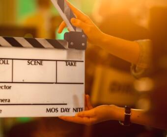 Clapperboard on a film set being held by hands, ready to slate a scene.