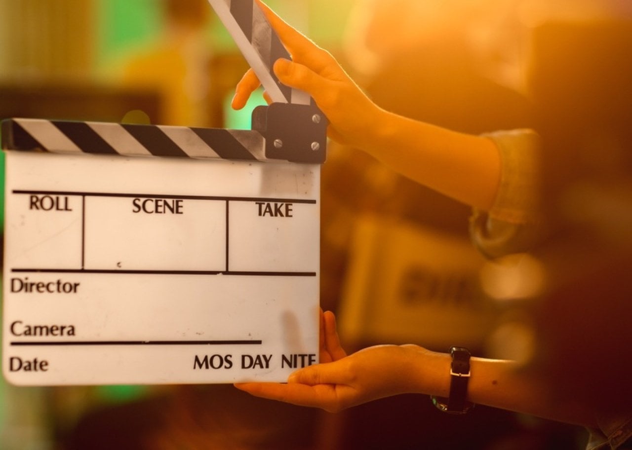 Clapperboard on a film set being held by hands, ready to slate a scene.