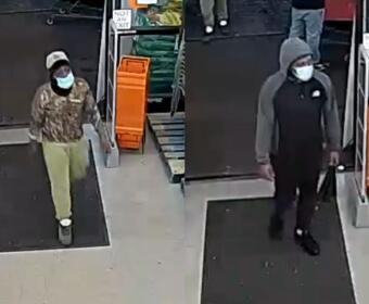 Two masked men enter a store through the entrance; left man wears camo hoodie and beige pants, white cap.