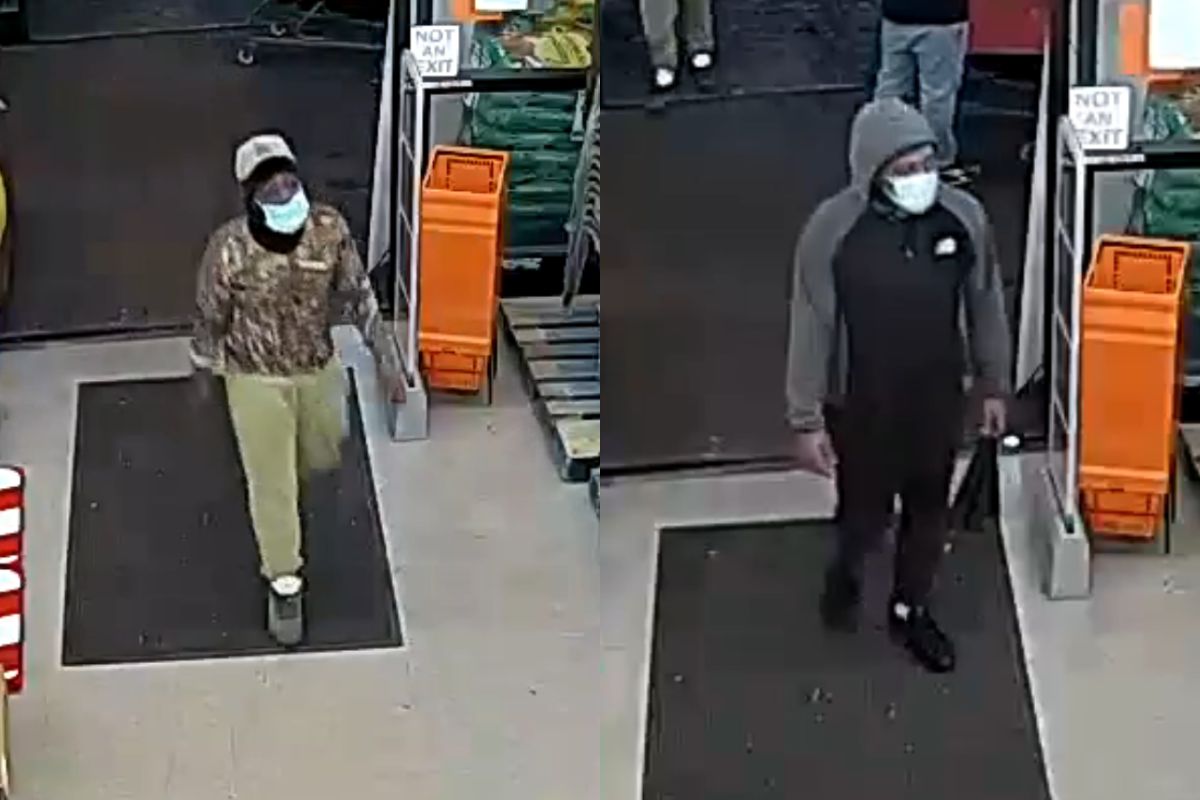 Two masked men enter a store through the entrance; left man wears camo hoodie and beige pants, white cap.