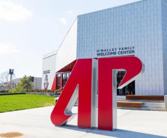 Large red '4D' sculpture in front of a modern white building with 'O'Malley Family Welcome Center' sign