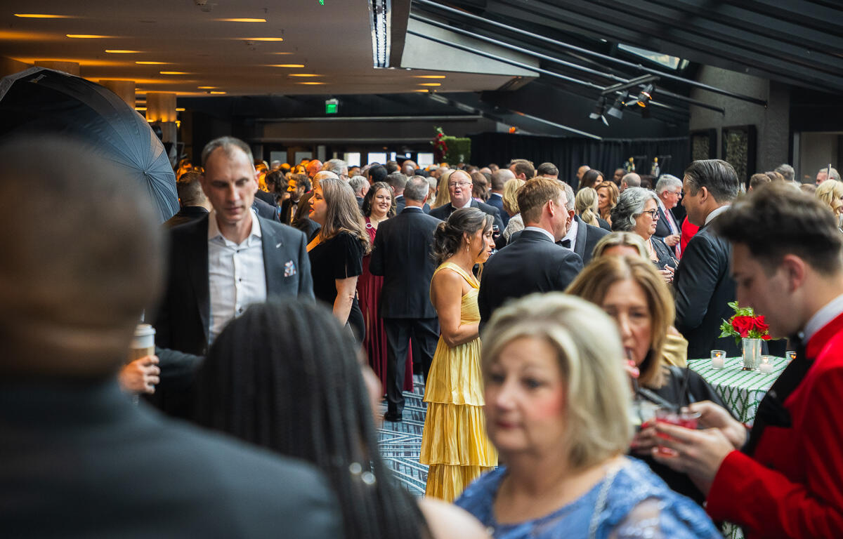 Crowded formal event with guests mingling in a modern indoor venue.