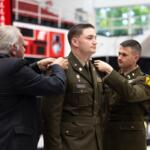 Soldier in dress uniform being pinned by an older man as another officer assists, during a ceremony (name tag 'MARTIN' visible).