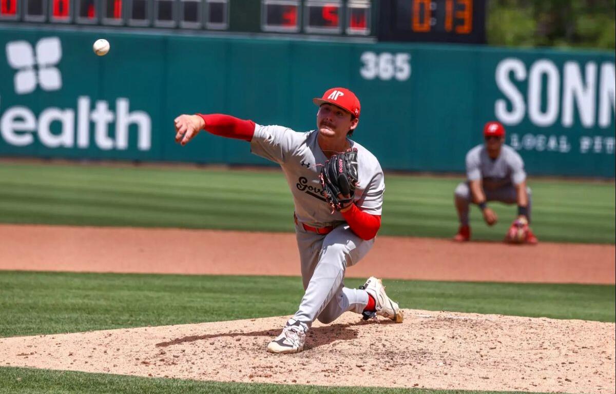 Right-handed pitcher in gray and red delivers a pitch from the mound during a daytime baseball game.