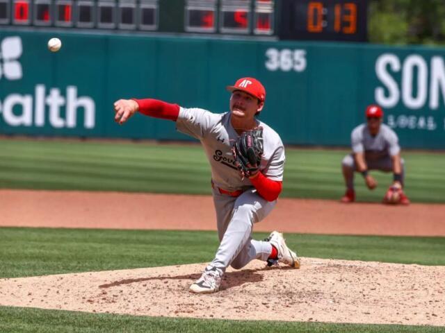 Right-handed pitcher in gray and red delivers a pitch from the mound during a daytime baseball game.