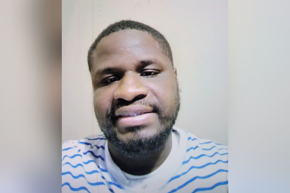 Close-up portrait of a man with short hair and a beard, wearing a white shirt with blue stripes, looking at the camera.