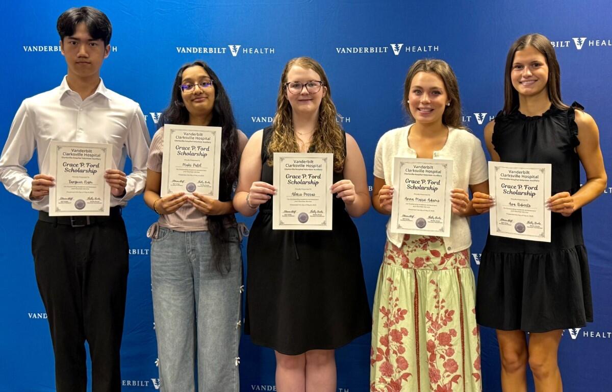 Five students stand in a row holding Grace P. Ford Scholarship certificates in front of a Vanderbilt Health backdrop.