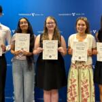 Five students stand in a row holding Grace P. Ford Scholarship certificates in front of a Vanderbilt Health backdrop.