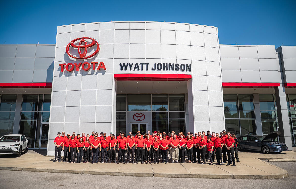 Group of Toyota Wyatt Johnson staff in red shirts posing outside the dealership.