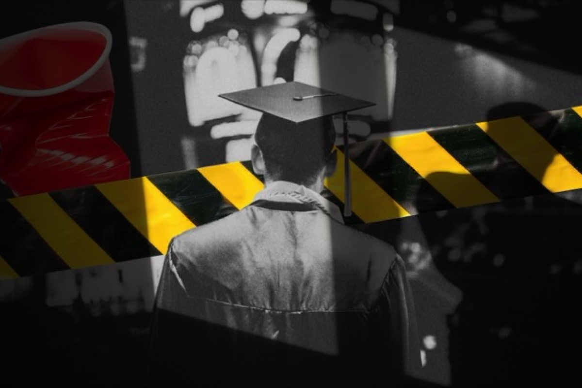 Graduate in cap and gown seen from behind with yellow-and-black caution tape across the foreground.