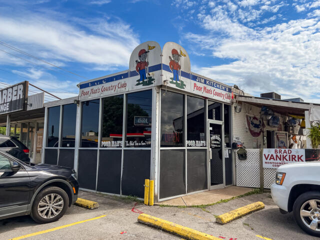 Exterior of Jim Kitchen's Poor Man's Country Club, a small diner with cartoon mascots on the roof and large glass windows in front.