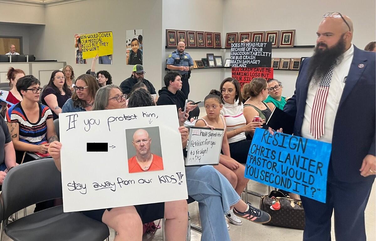 Attendees holding signs up toward the board at the CMCSS formal school board meeting on July 21, 2026. (Jazmin Logan)