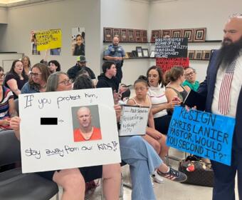 Attendees holding signs up toward the board at the CMCSS formal school board meeting on July 21, 2026. (Jazmin Logan)