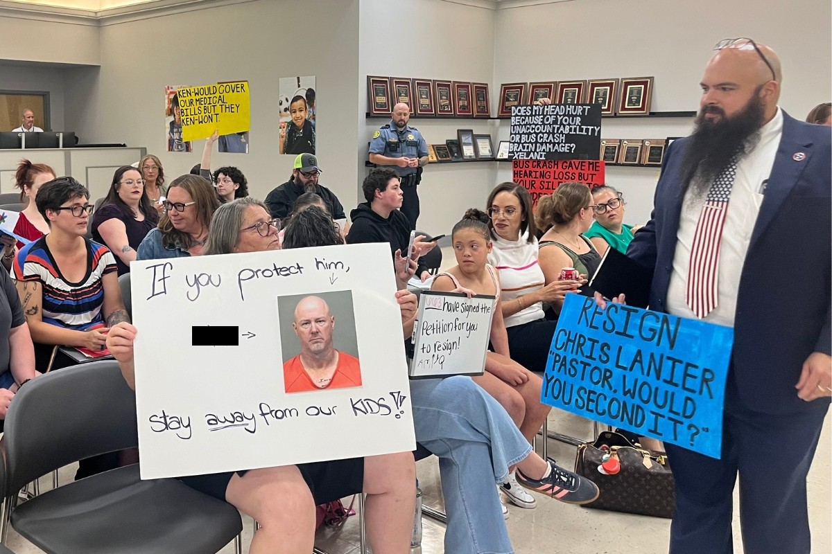 Attendees holding signs up toward the board at the CMCSS formal school board meeting on July 21, 2026. (Jazmin Logan)
