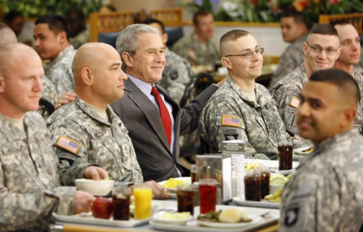 President George W. Bush is flanked by Sgt. 1st Class Rick Elza, left, of Lexington, Ky., and Capt. Rolando Perez of Mayaguez, Puerto Rico, at lunch on Nov. 25, 2008, at Fort Campbell's Son Cafe. (White House photo by Eric Draper)